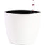 The white self-watering planters displayed in different environments like an office desk, windowsill, or patio.